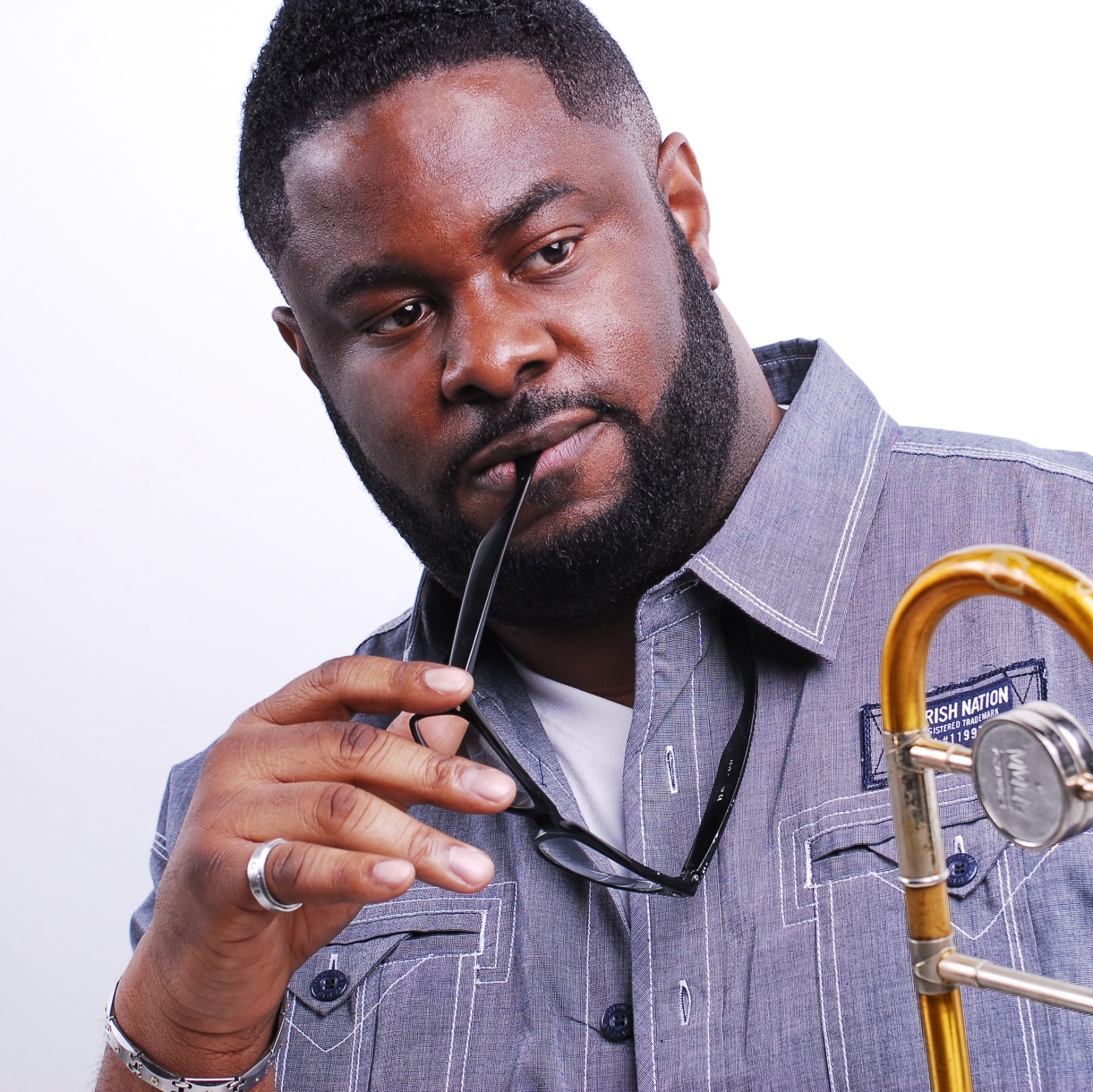 Jermaine Bryson holding glasses beside his trombone